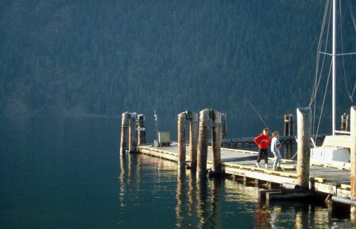 Two people fishing on a dock.
