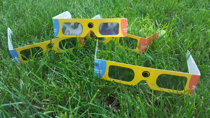 Four eclipse glasses sitting in grass.