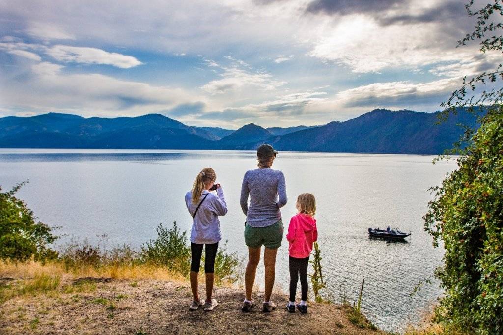 mom and daughters looking at a lake