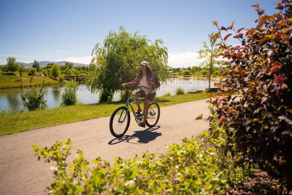 woman on bike on paved path near pond