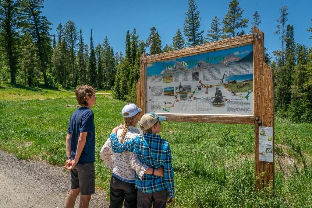 three people standing in front of interpretive sign