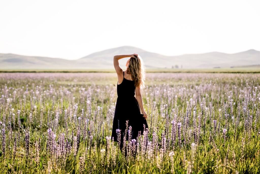 a woman standing in a wide-open field of camas lilies at Camas Prairie Centennial Marsh Wildlife Management Area