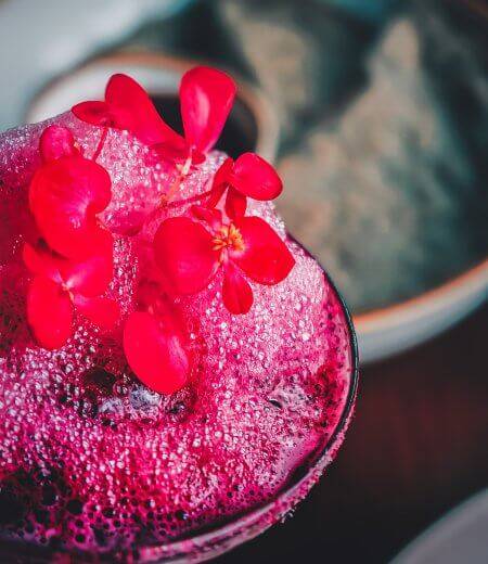vibrant pink cocktail with hibiscus flower on top