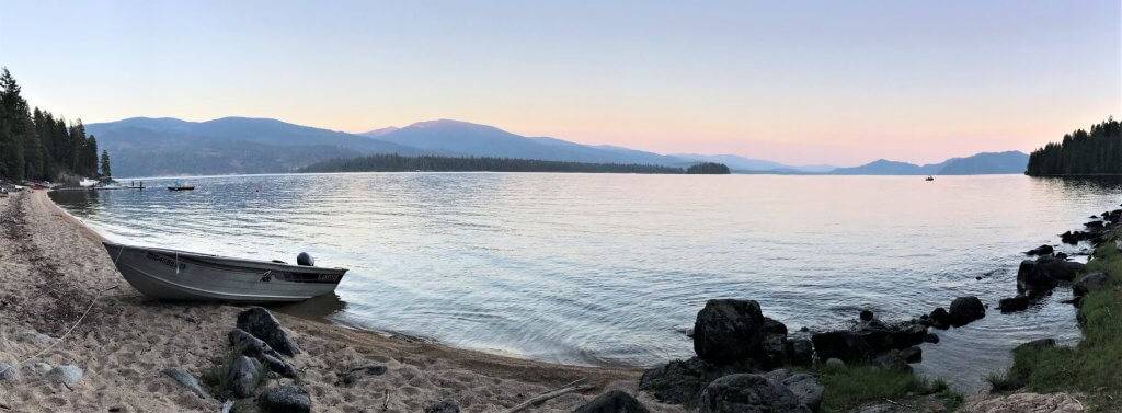 wide shot of lake at sunset with boat pulled up on to sand
