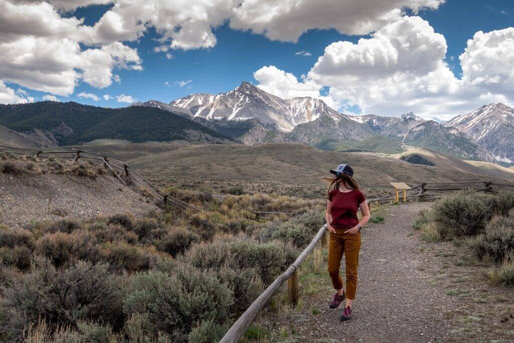 woman walks on asphalt trail overlooking historical geological site