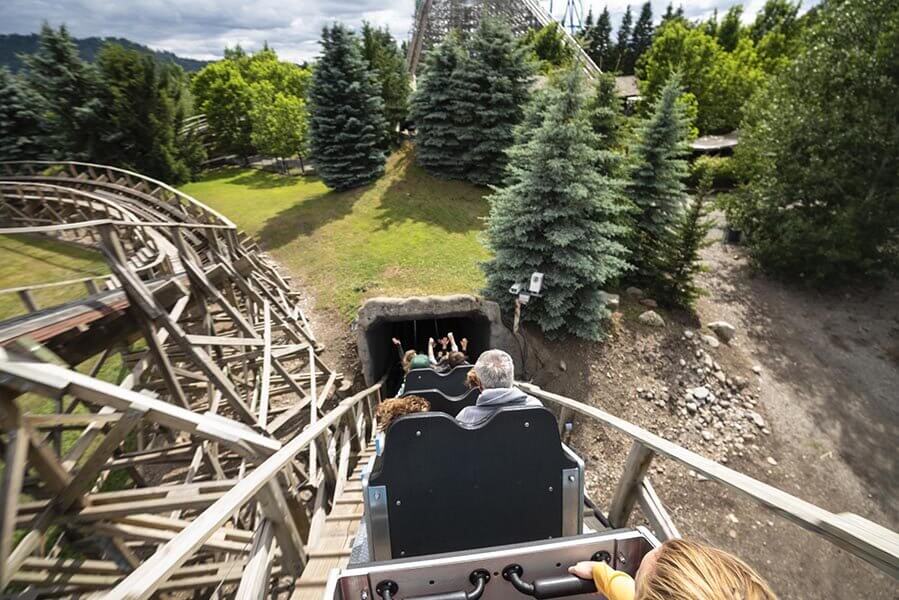 People ride a roller coaster as it descends into a tunnel.