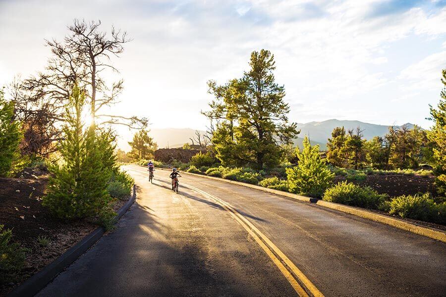 Two kids ride their bikes at sunset.