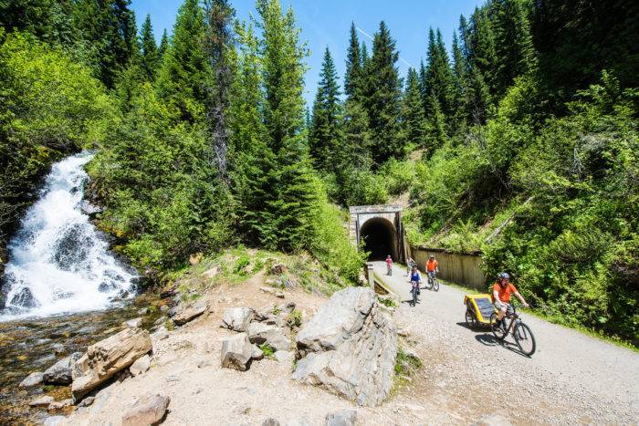 family rides bikes near waterfall