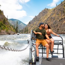 A man and woman smile as they ride a jet boat through the Salmon River.