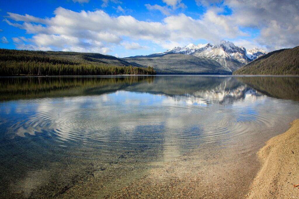 A crystal clear lake beneath snow-covered mountains.