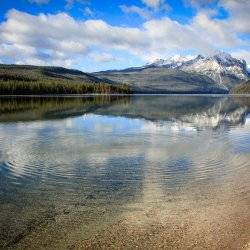 A crystal clear lake beneath snow-covered mountains.