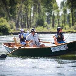 A man and his two grandsons sit in a row boat and cast ines into the South Fork of the Snake River.