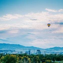 An air balloon floating over a city landscape.