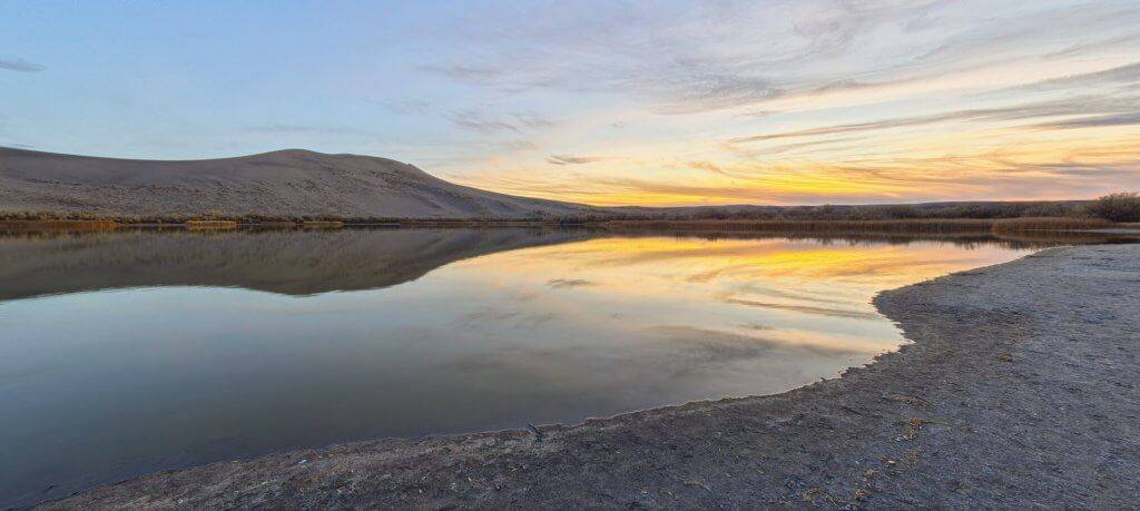 A picture of sand dunes with a river running between them.