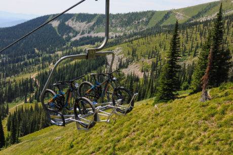 A pair of mountain bikes being transported up a ski lift during the summer.