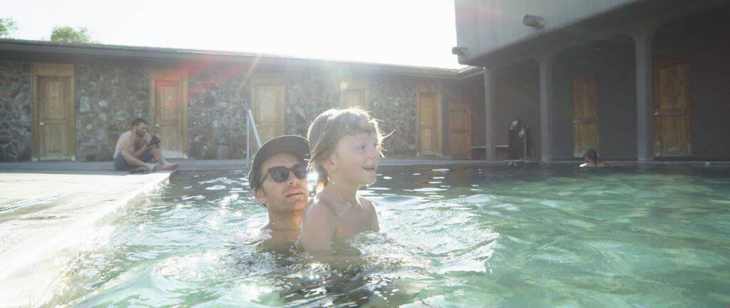 dad and son soaking in hot pool