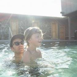 dad and son soaking in hot pool