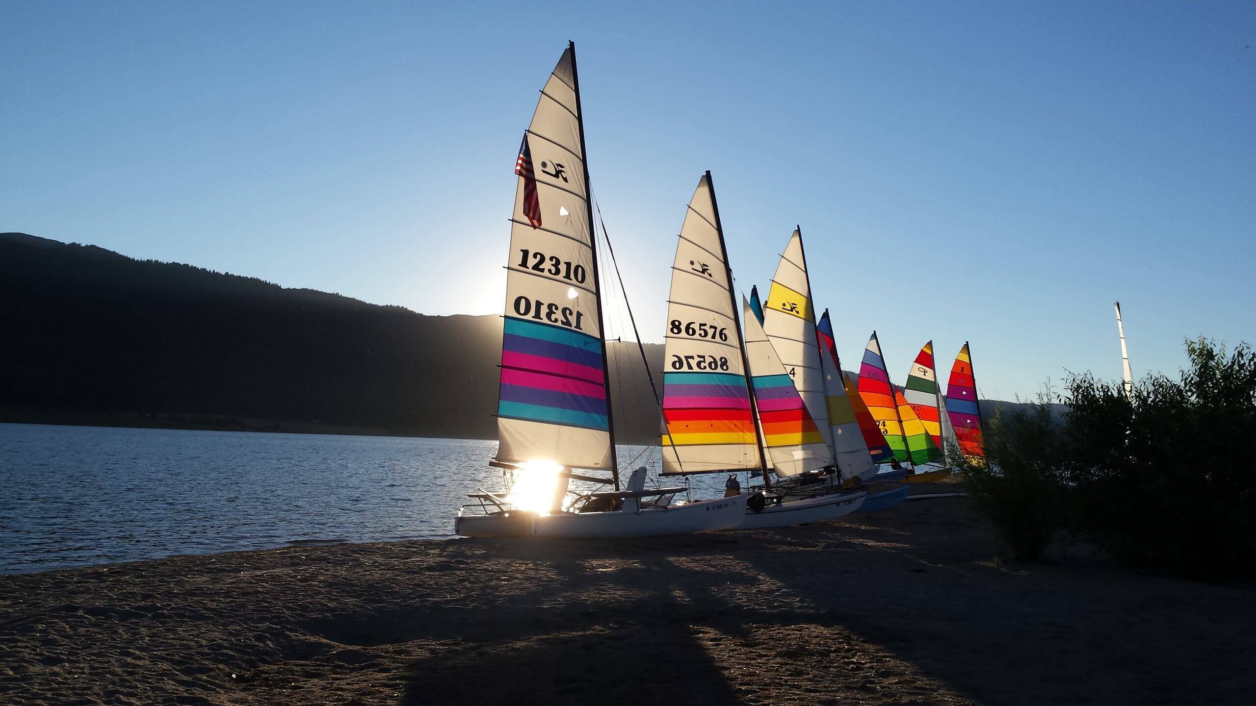 Sailboats with colorful sails docked on the beach at Lake Cascade.