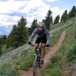 A man mountain biking on a trail during the summer.