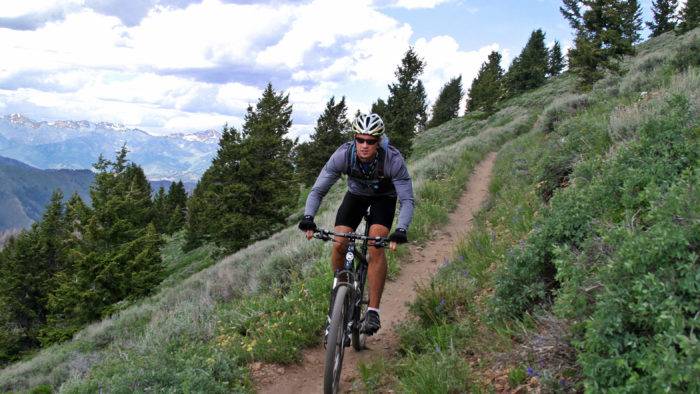 A man mountain biking on a trail during the summer.