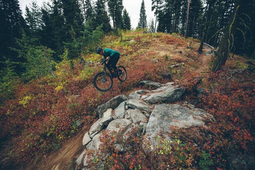 A mountain biker jumps over rocks at Jug Mountain Ranch.