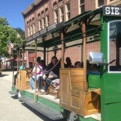 A group of people riding a trolley past a brick building on the Sierra Silver Mine Tour.