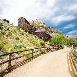 A dirt path lined by a wooden fence leading toward a historic wooden building at Bayhorse Ghost Town.