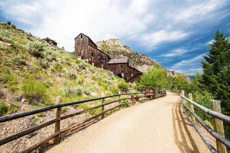 view of a hillside trail lined with wooden rails and a tall wooden building 