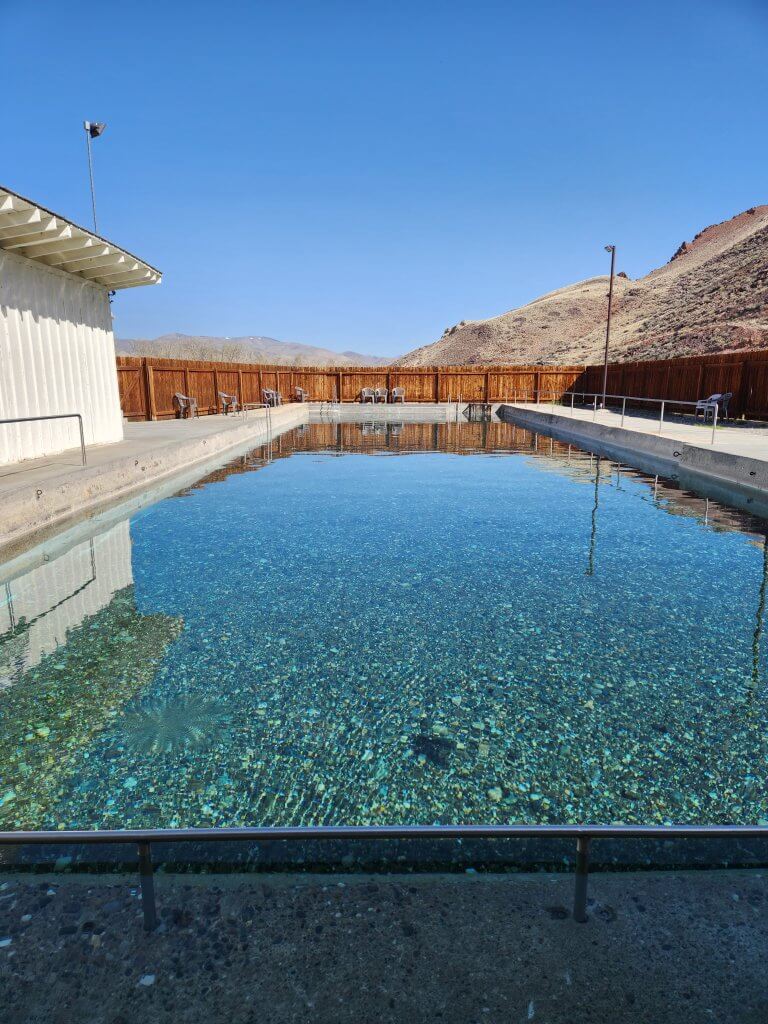 An empty natural rectangular hot pool filled with turquoise water that allows you to see the gravel bottom of the pool at Challis Hot Springs.