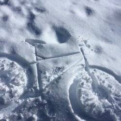 An imprint of a bike that was once laying in the snow.