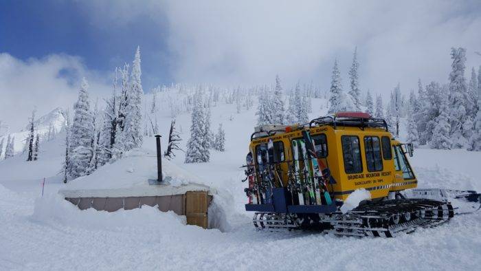 A snow cat stopped at a yurt.