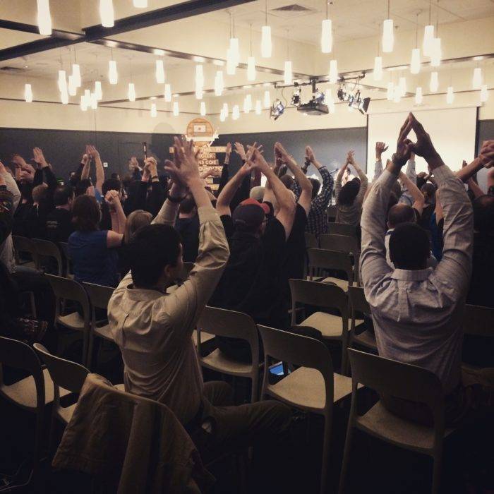 An audience stretching in their chairs before a seminar