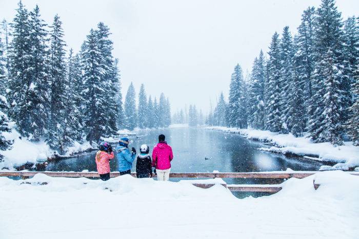 A family of four looking out over a river in the winter.