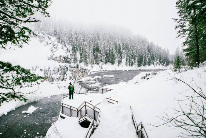 A man looking at a waterfall in the winter.