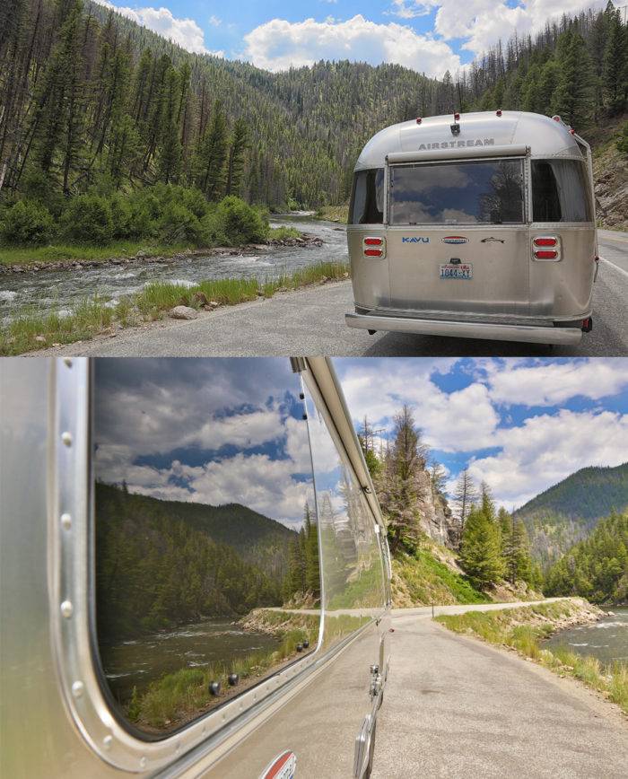 Airstream trailer along winding riverfront road.