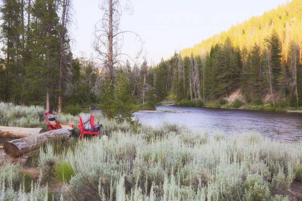 Camp chairs set up riverside to enjoy the early evening view.