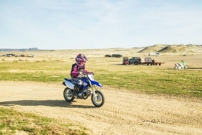 A young girl riding a dirt bike on a trail.