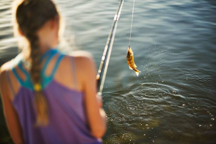 A girl reeling in a fish.