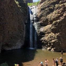 A group of people playing in the water at a waterfall.