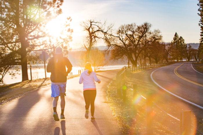 A couple running next to a lake at sunset.