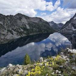 An edited photo of an alpine lake within a mountain peaks.