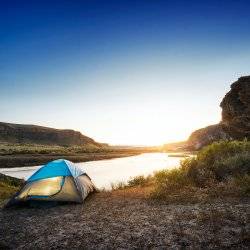 A tent set up along a river.