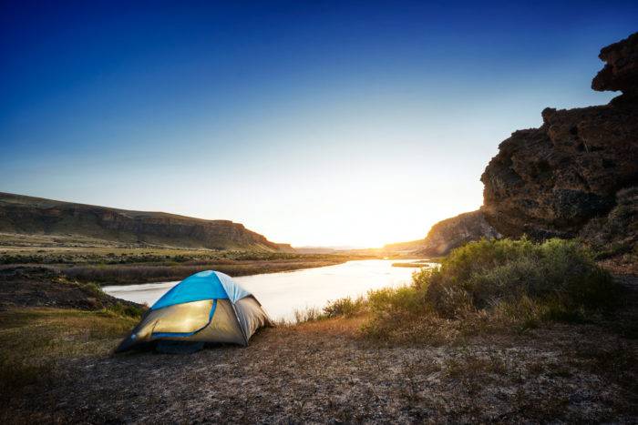 A tent set up along a river.