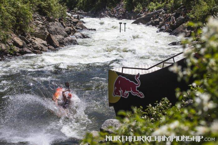 Kayaker jumping off a ramp into river.