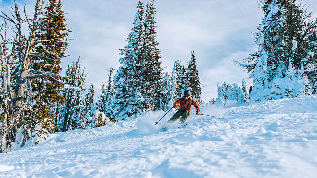 A woman in orange skis down a slope at Brundage Mountain Resort.