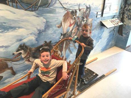 Two boys on a dog sled inside the Geotourism Center.