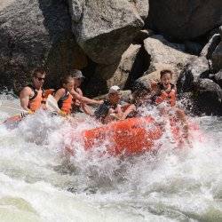 A family laughs mid-adventure as they raft down the North Fork Payette River on the Cabarton River Run in a great splash.