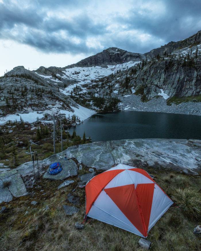 Tent on a rocky point above a mountain lake.