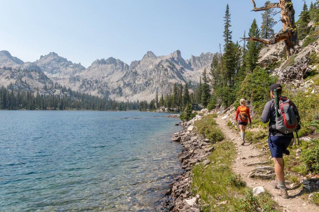 Hikers walking along side a lake.