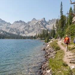 Hikers walking along side a lake.